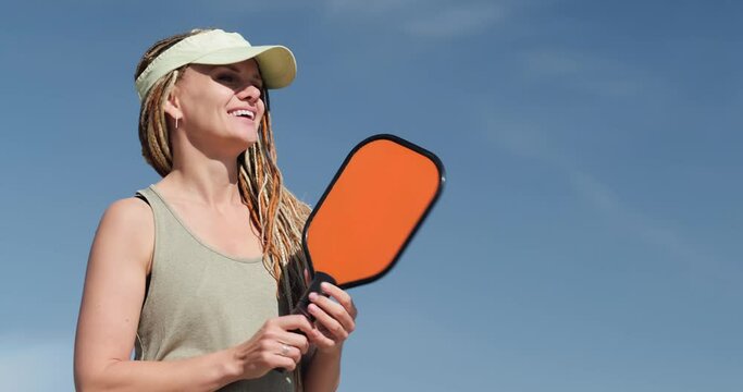 Portrait pickle ball player, woman playing pickleball game, hitting pickleball yellow ball with paddle, outdoor sport leisure activity.
