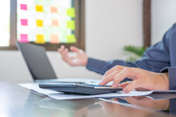Businessmen bookkeeper hand use calculator and laptop doing account for paying tax on desk in working office
