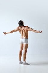 Fototapeta premium Rear view image of man posing shirtless in underwear against grey studio background. Relief back, muscular, healthy body. Concept of men's beauty, body care, sport, wellness, healthy lifestyle, ad