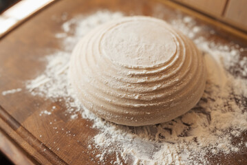 Fototapeta na wymiar Dough in round form of future bread on cutting board, powdered with flour. Close up of homemade bread in the kitchen before baking