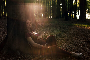 dreamy portrait of pregnant woman lying in woods