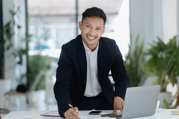 Portrait of candid happy asian businessman working in office.