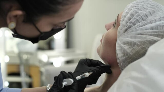 real-life example of non-surgical face lifting, as beauty doctor injects patient's jowls with syringe. procedure, aimed at sculpting facial contour, is shown in authentic and direct manner