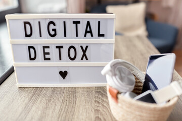 technology concept - digital detox words on light box and different gadgets on blue background