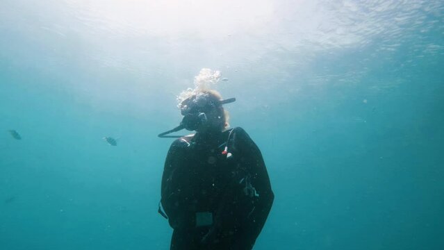 Scuba Diver Ascending to Surface with Bubbles and Great Reflection of Sun in Water