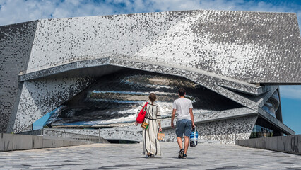 Couple marchant vers la Philharmonie de Paris concert hall in La <Villette, Paris, France