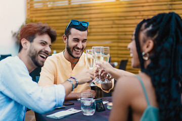 Toast of Friendship at the Restaurant - Trendy young man leads a champagne toast with diverse...