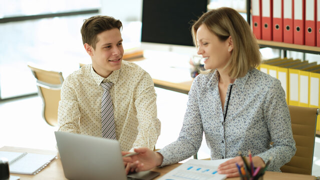 Confident businesswoman pointing at laptop screen teaching new trainee employee in office. Seo helping intern at workplace