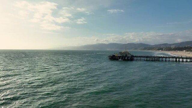 Ocean waves of Santa monica beach with pier included and mountains on the background