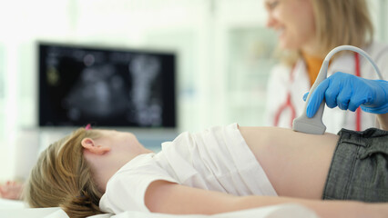 Doctor conducts ultrasound examination of internal organs of child in clinic. Abdominal pain in...