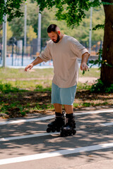 Fototapeta premium Young guy with a beard learns to rollerblade in a city park concept of wanting to learn new things and body positivity 