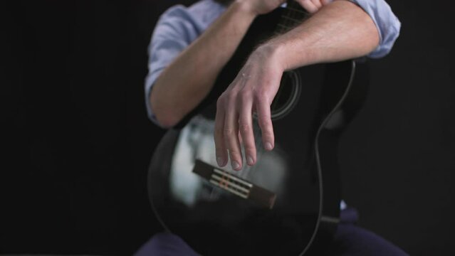 musical instrument, male musician with guitar in his hands on a dark background