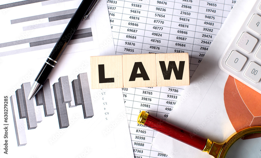 Poster law text on wooden block on graph background with pen and magnifier
