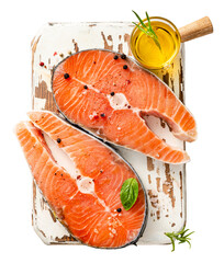 Fresh raw salmon steaks on wooden board with olive oil. Top view of fish.