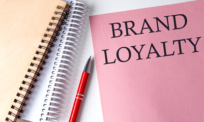 BRAND LOYALTY word on the pink paper with office tools on white background