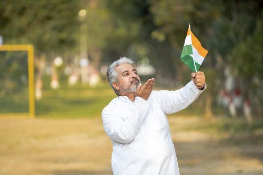 Indian senior man waving national tricolor flag.