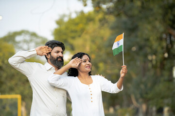 indian couple saluting together of tricolor flag at garden.