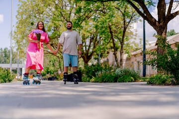 Obraz premium Young couple guy and girl rollerblading in summer in a city park while dating plus size models