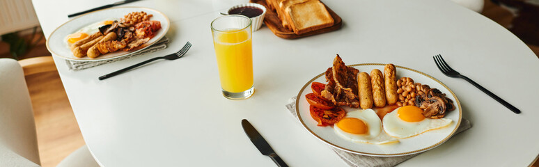 Delicious breakfast with fried eggs, sausages and orange juice on table at home, banner