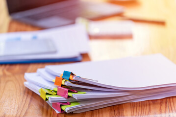 Paper documents are stacked on wooden desks at the workplace.