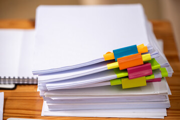 Paper documents are stacked on wooden desks at the workplace.