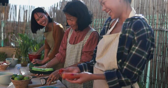 Asian family cooking thai dinner together while preparing papaya salad with fresh spicy dressing at home patio outdoor 