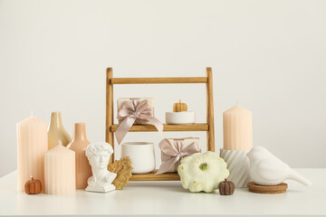 Fototapeta na wymiar Candles, figurines and wooden shelves on beige background