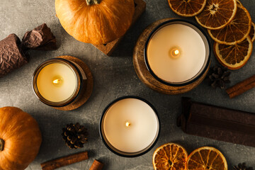 Candles, cinnamon, pumpkins and orange on gray background, top view