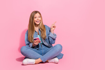 Photo of cheerful pretty girl wear stylish outfit hand hold iphone demonstrate empty space nice offer isolated on pink color background