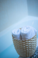 Fototapeta na wymiar twisted white towels in a wicker bag in the bathroom, twisted bath towels in a basket, the concept of home comfort and coziness