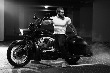Fototapeta na wymiar Athletic bearded biker man riding motorbike isolated on indoor parking
