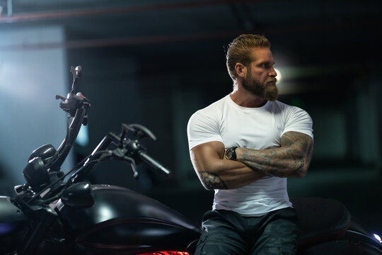 Athletic Bearded Biker Man Riding Motorbike Isolated On Indoor Parking