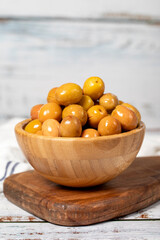 Big green olive at wooden bowl. Olives on a white wood background. Mediterranean food. vegan food