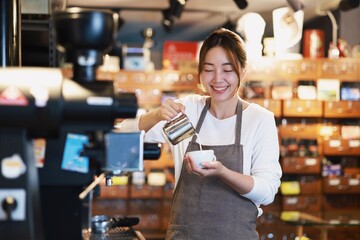 Cheerful woman making a coffee cup in cafe,Barista holding a cup of hot coffee for the first Morning.