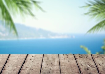 Empty wood desk over sea and palm leaves