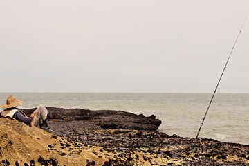 A Relaxed Fisherman Awaits His Catch Against a Beautiful Coastal Backdrop