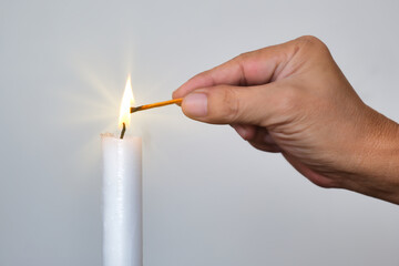 Close-up hand igniting a candle using safety match stick