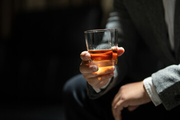 Businessman sitting and holding glass of whiskey..