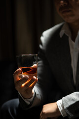 Businessman sitting and holding glass of whiskey..