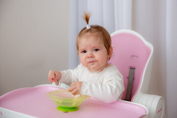 cute baby eats in a high chair made of silicone baby dishes. Baby food, space for text