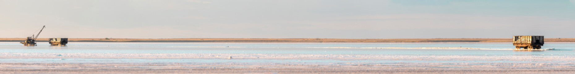 panorama of the salt lake at sunset and abandoned wagons in the salt