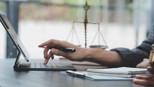 Justice and law concept.Male judge in a courtroom with the gavel, working with, computer and docking keyboard, eyeglasses, on table in morning light