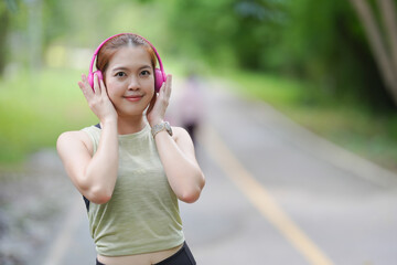 Portrait of Asian sporty girl with pink headphone and be happy to exercise at the park