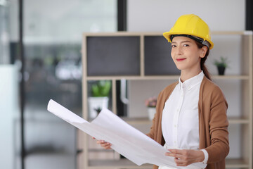Portrait of smiling woman engineer is happy with floor plan blueprint projects in the office.