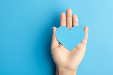 Promoting positive mental health. Hans holding a paper heart isolated on a blue background. High quality photo