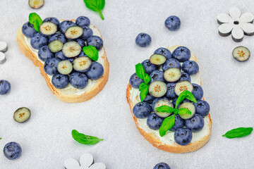 Fresh bread sandwiches with sweet blueberries, cream cheese and basil leaves. Good morning concept