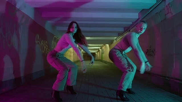 A guy and a girl are dancing urban sexy dances. Beautiful movements of modern dance in the neon light of an underground passage in the city. High quality 4k footage