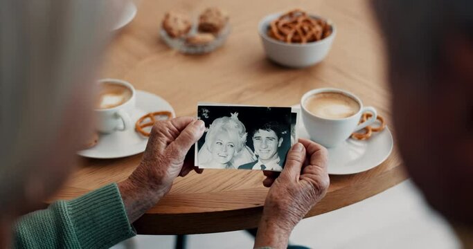 People, hands and photograph with memory at home for nostalgia, history and to remember. Closeup of senior friends at tea table with pictures of old album, marriage and photography in retirement
