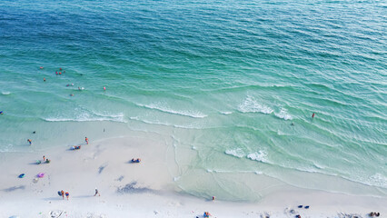 Gorgeous shade of blue and crystal-clear turquoise water of Santa Rosa beach, brilliantly white sandy shore with people swimming, relaxing laid-back vibe charming Walton County, Florida, USA
