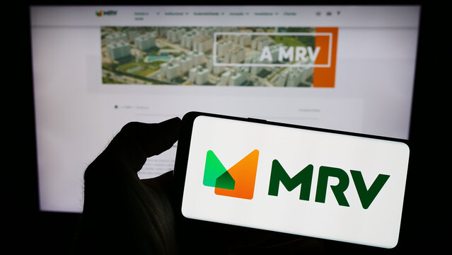 Stuttgart, Germany - 07-26-2023: Person holding cellphone with logo of company MRV Engenharia e Participacoes SA on screen in front of business webpage. Focus on phone display.